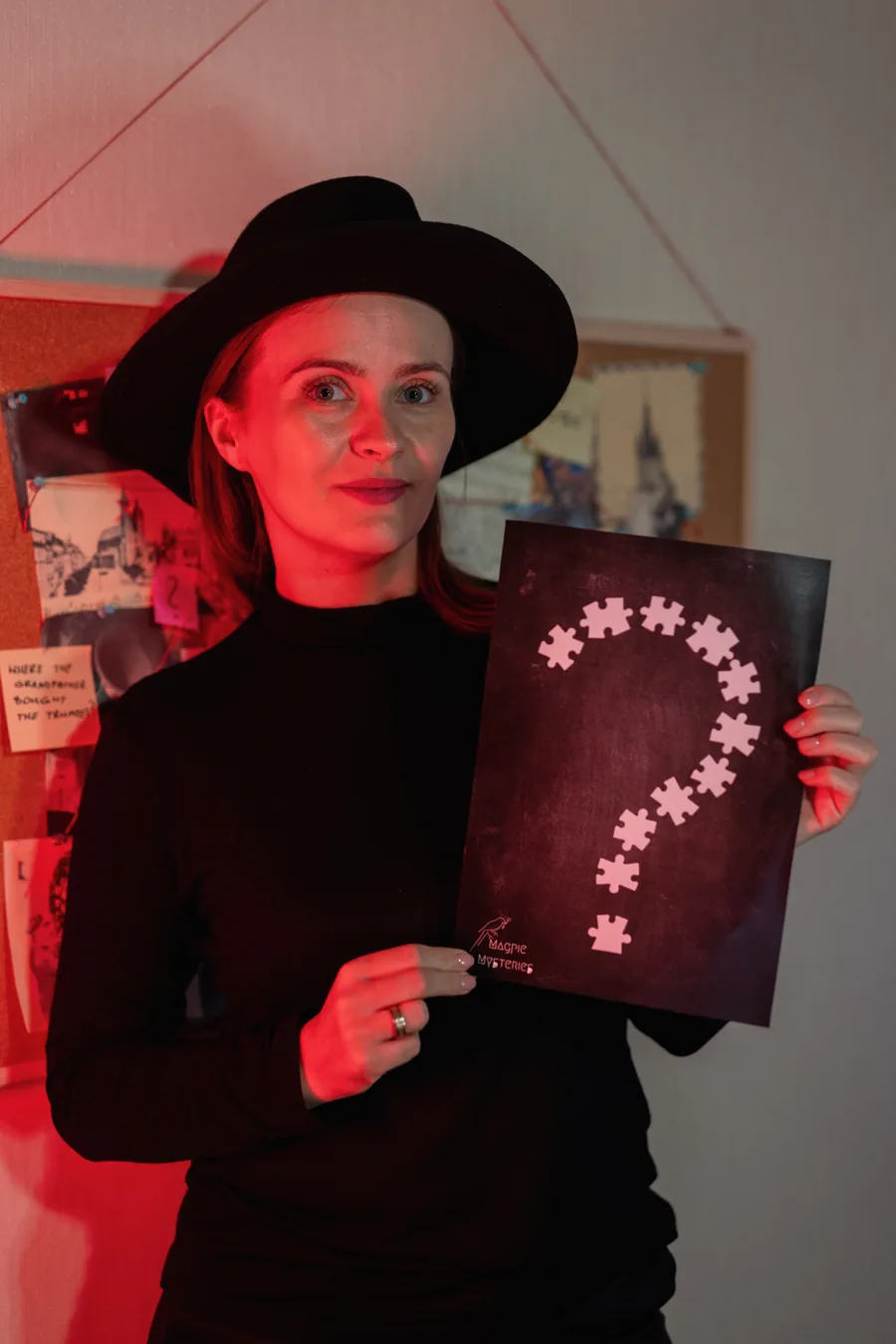 A host holding a question-mark sign at a murder mystery event